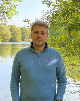 Tom Wust standing in front of a lake.