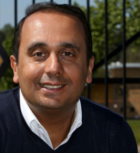 Head shot of Paul Uppal in front of railings.