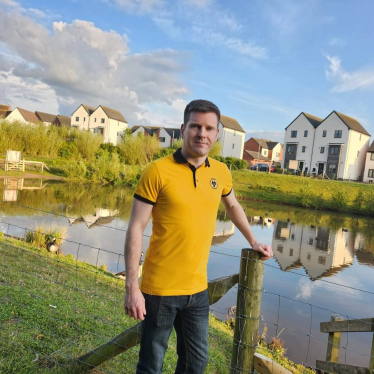 Photo of Adam Collinge infront of a small lake.